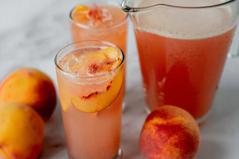 Peach beer cocktail in a glass and pitcher