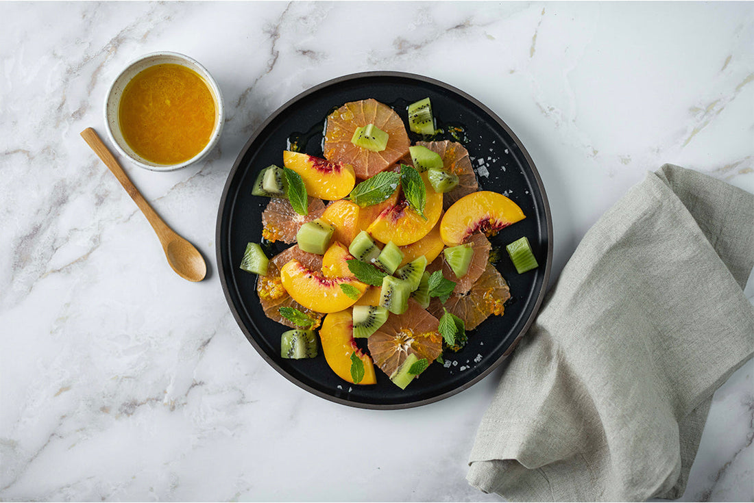 Peach, grapefruit, and kiwi salad on a marble countertop
