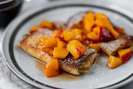 Cheese blintzes topped with peaches