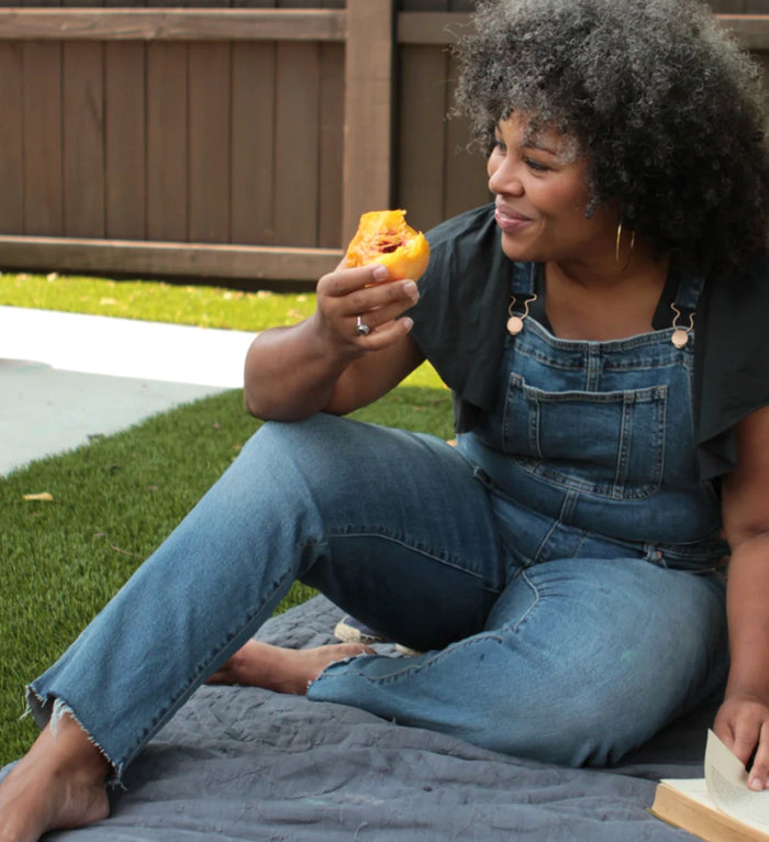 Woman eating a peach in her backyard